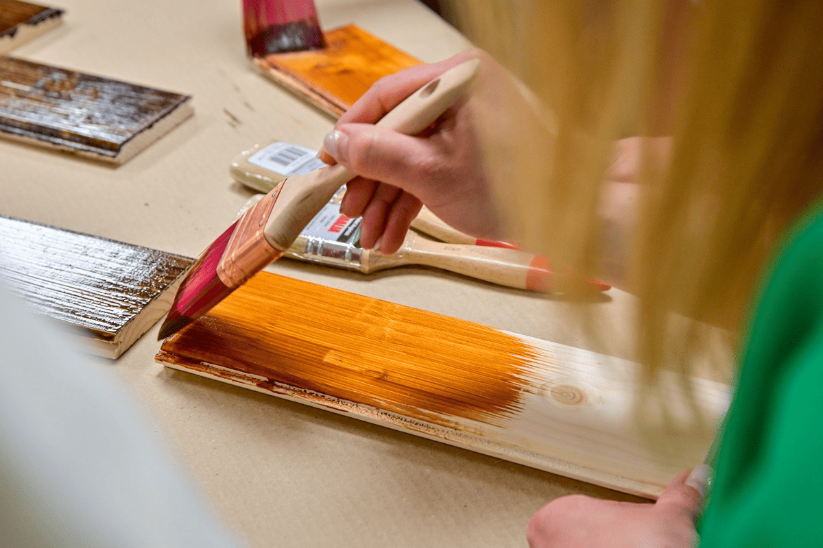 a person painting a wood with paintbrushes